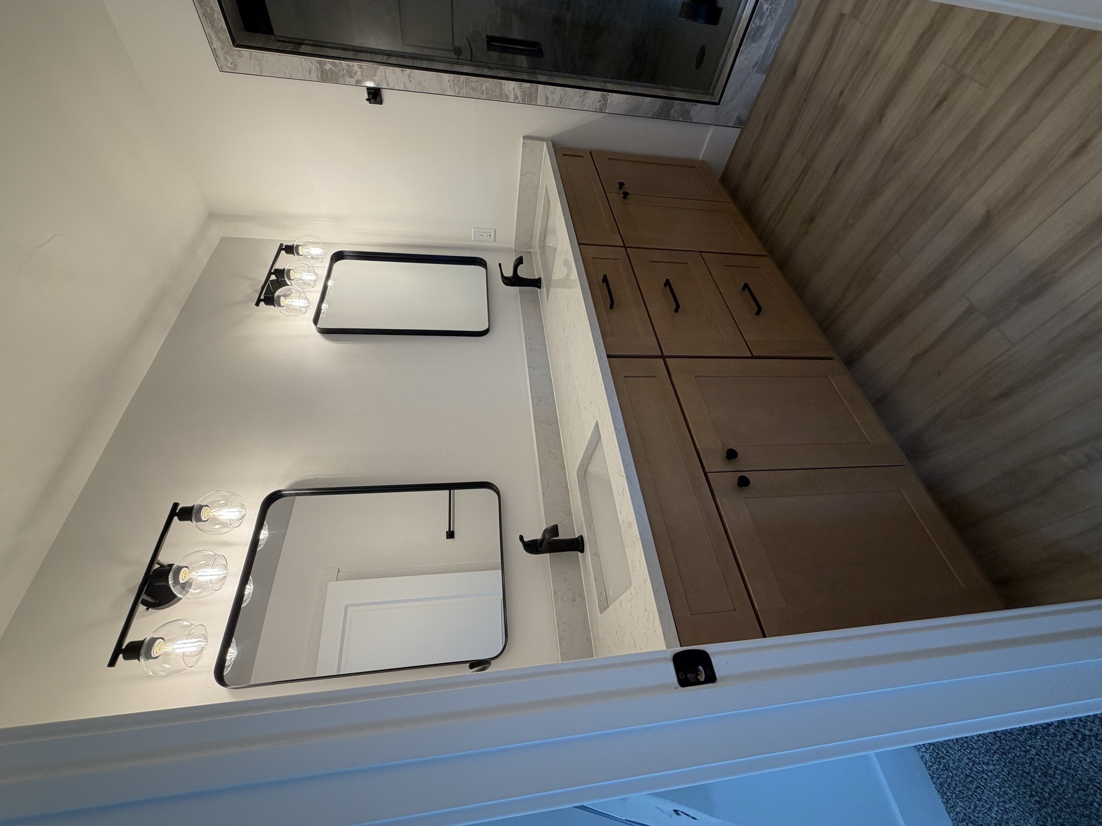 Double vanity bathroom with twin round mirrors and globe wall sconces