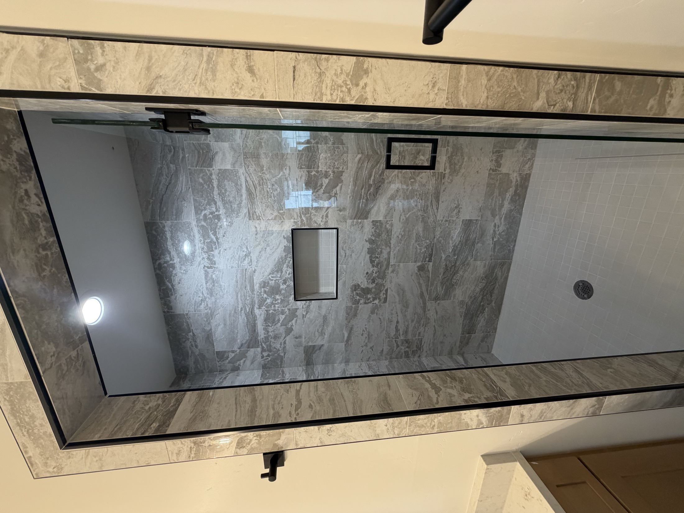 Walk-in shower with full glass enclosure and stone tile walls