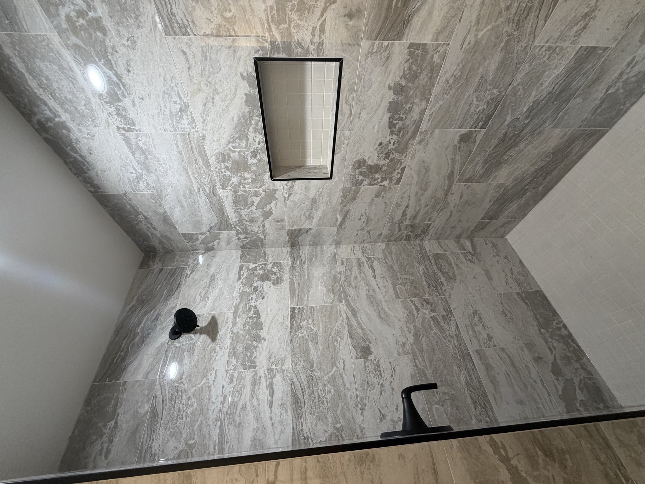 Custom shower with large format gray marble tile and matte black hardware