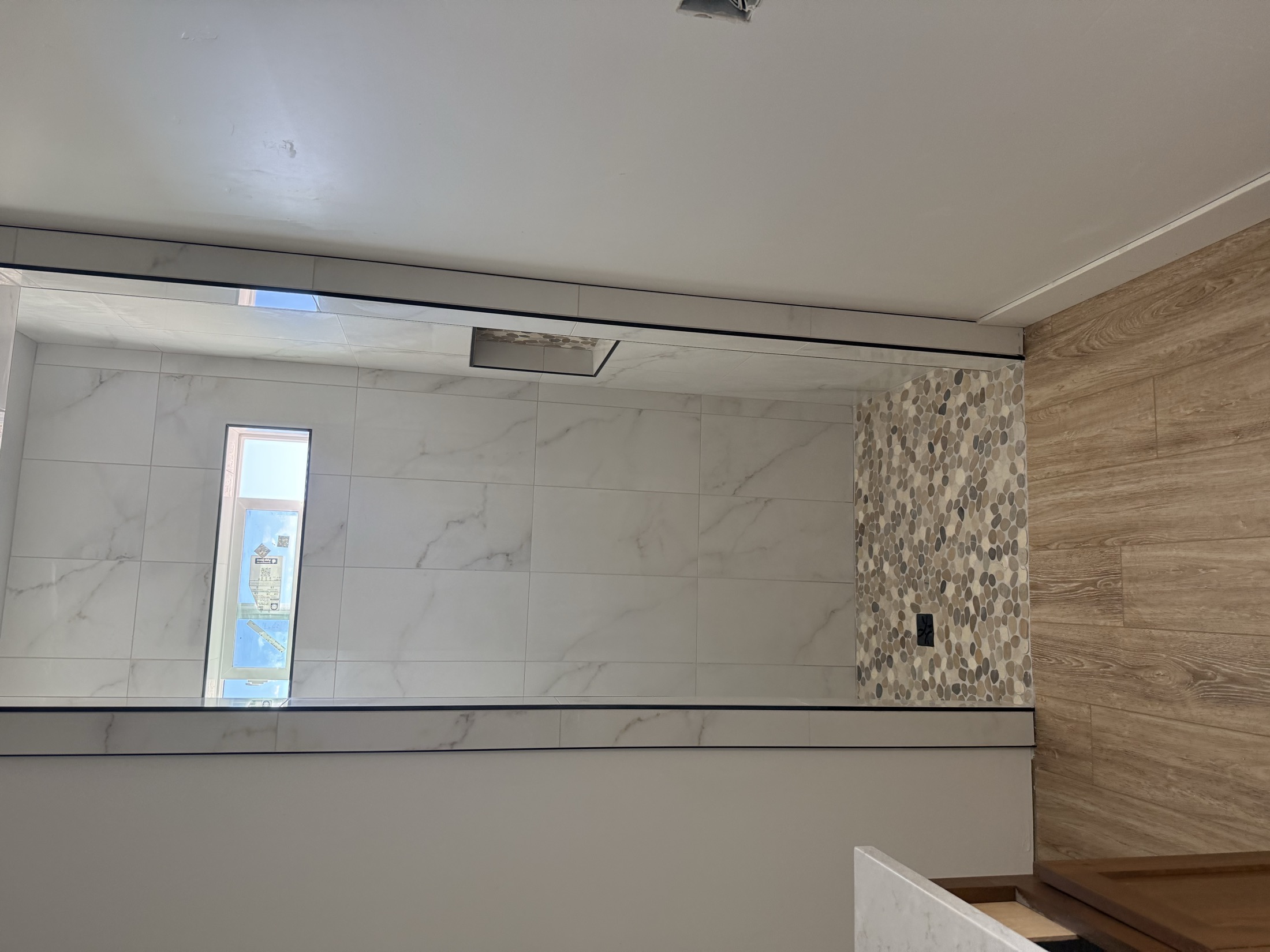 Custom tile shower with pebble accent strip and wood-look floor