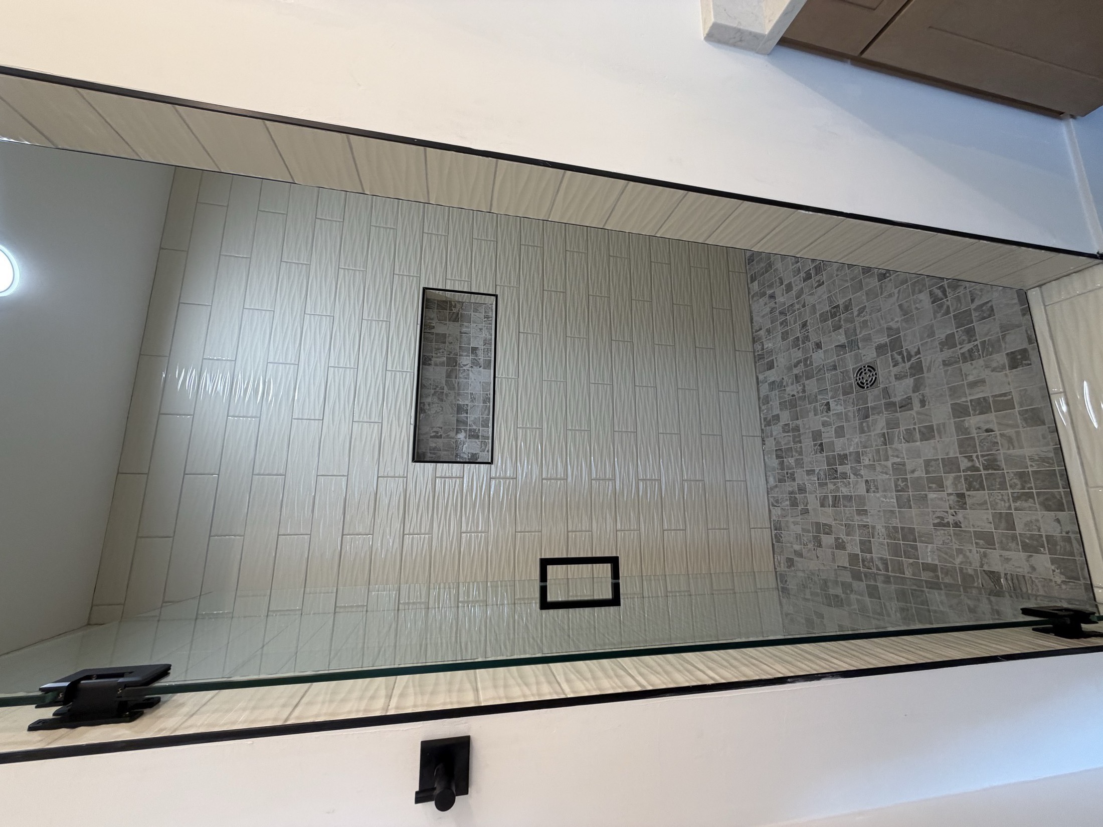 Tile shower with vertical white subway tile and pebble accent