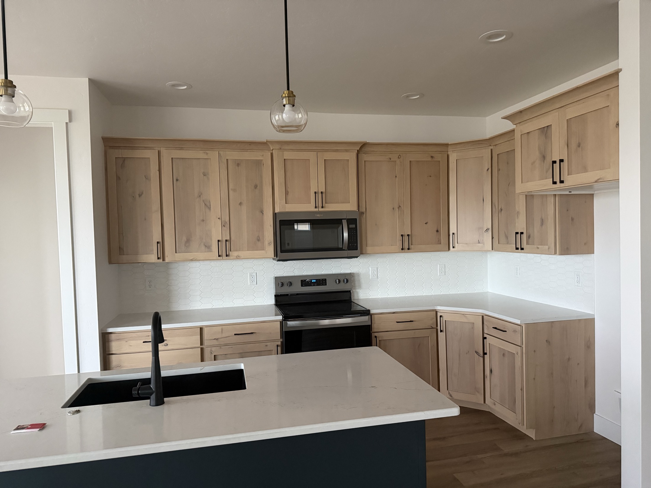 Custom knotty alder kitchen with quartz counters and pendant lighting by Skyline Custom Homes