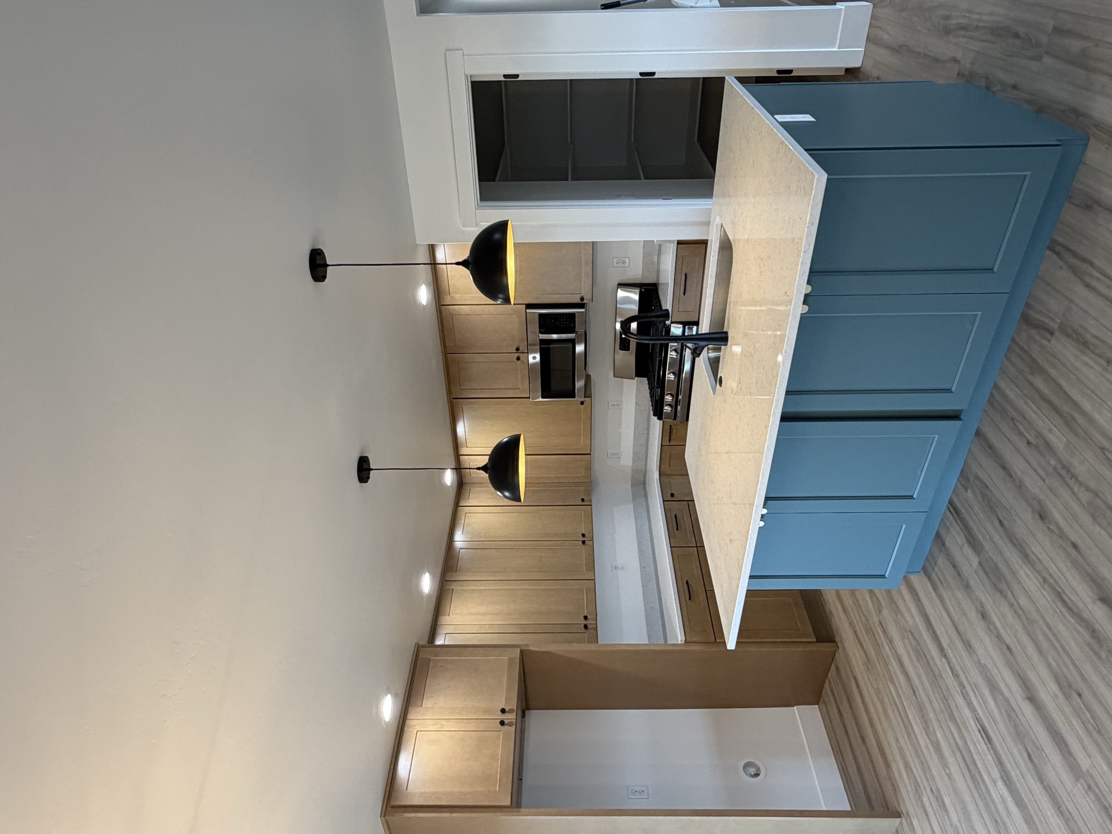 Custom kitchen with blue island, hood vent niche, and pendant lighting