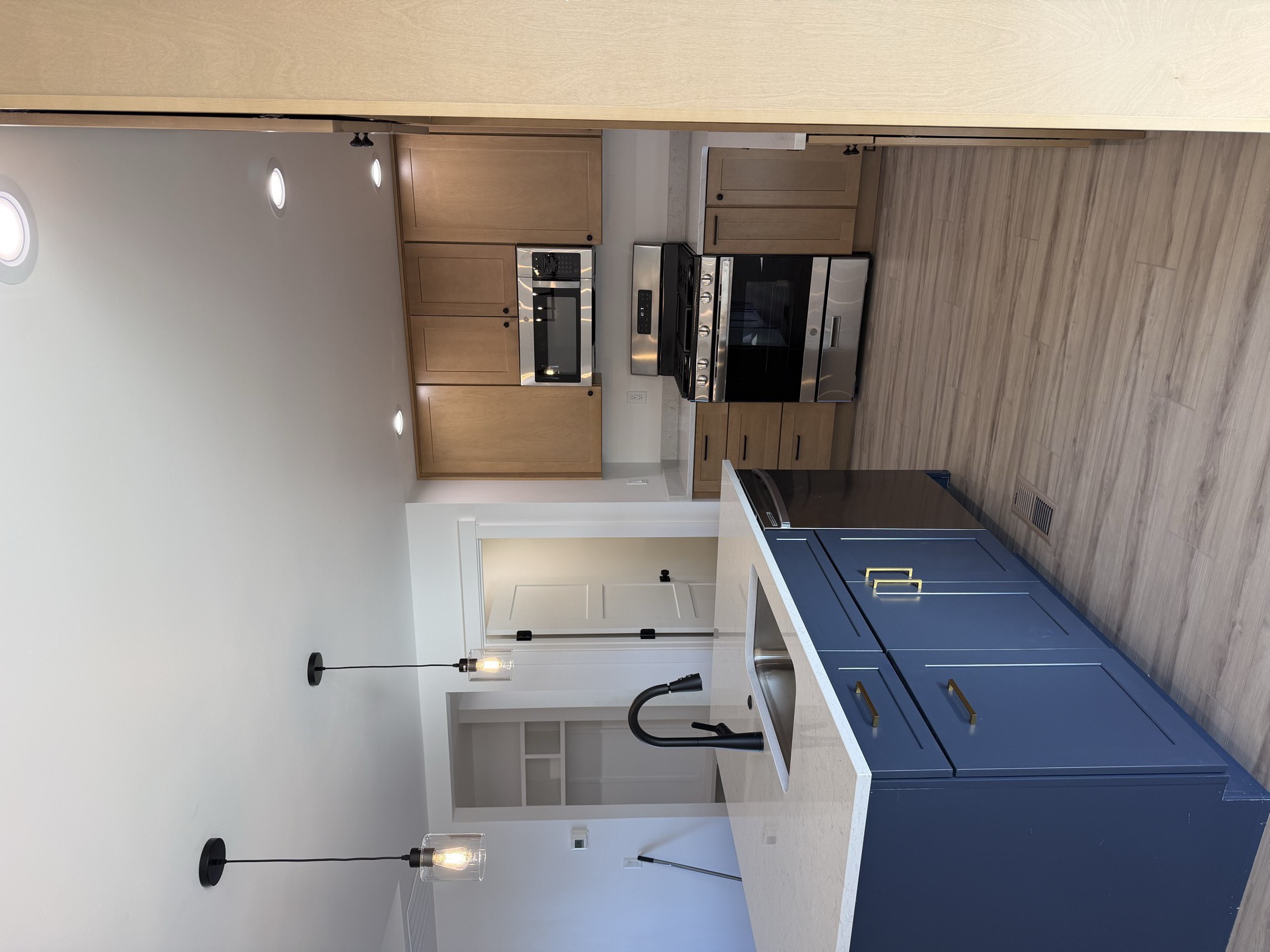Custom kitchen with double wall oven and navy island cabinets