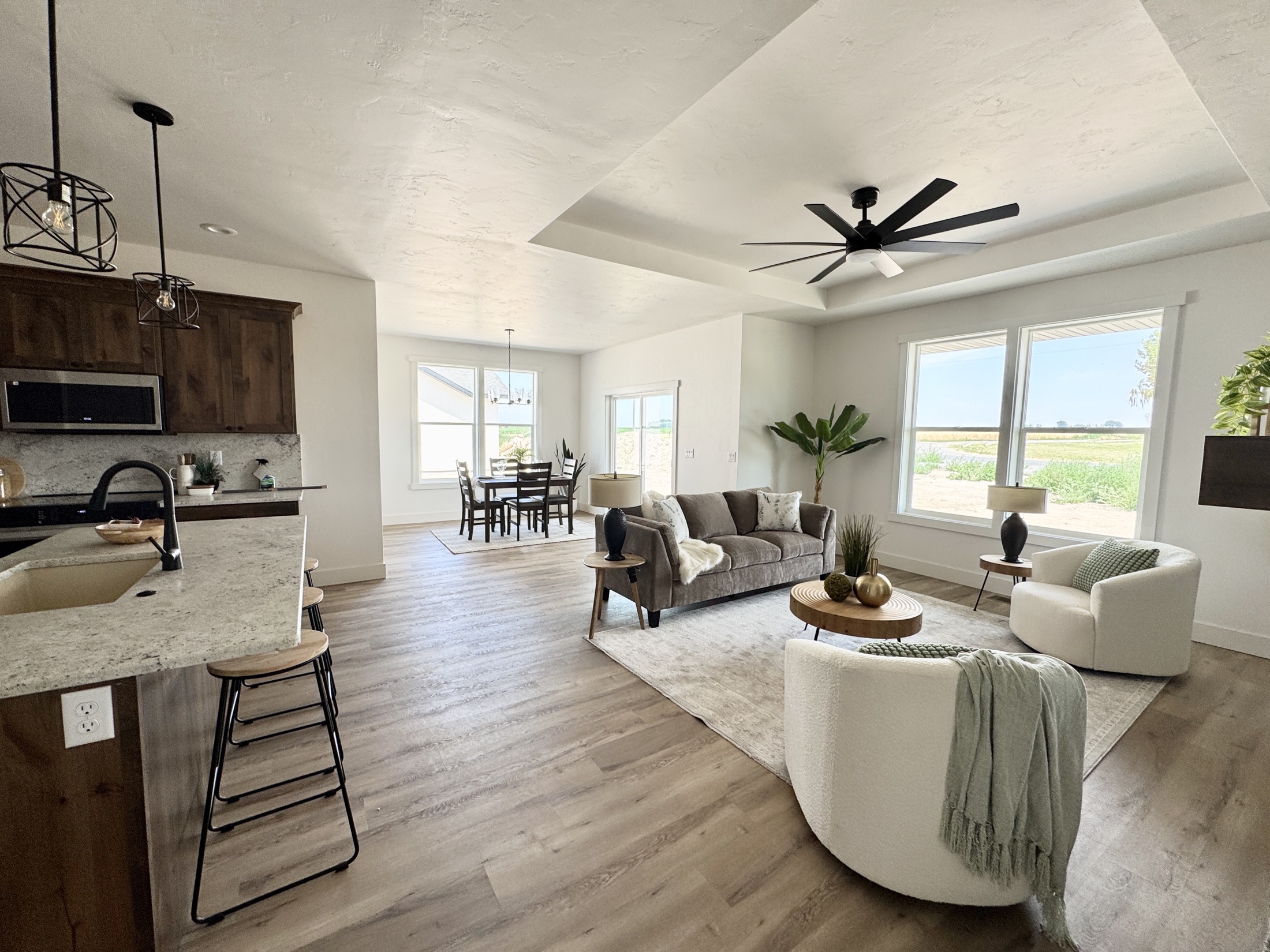 Open concept living room and kitchen with tray ceiling and ceiling fan